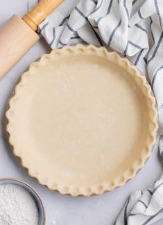 an uncooked pie crust next to a rolling pin