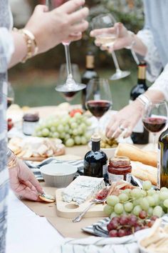 several people standing around a table with wine and cheese