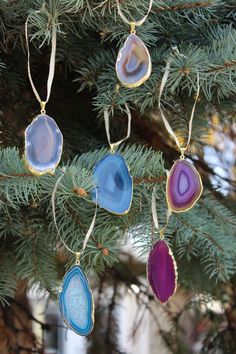 ornaments hanging from a pine tree with blue and purple agate glass pieces on them