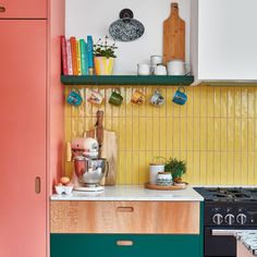 a kitchen with green and pink cabinets, white counter tops, and wooden shelves on the wall