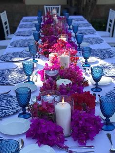 the table is set with blue and white china plates, purple flowers, and candles