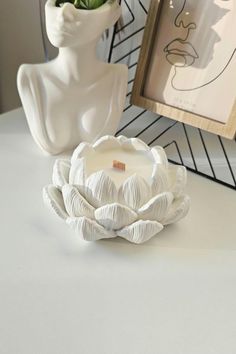 a white candle sitting on top of a table next to a vase filled with flowers