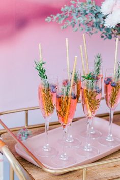 four glasses filled with champagne and garnish on a tray