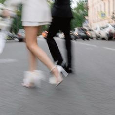 two people are walking down the street with umbrellas over their heads and shoes on