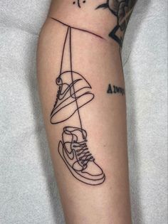 a person with a tattoo on their arm holding a pair of sneakers and a surfboard