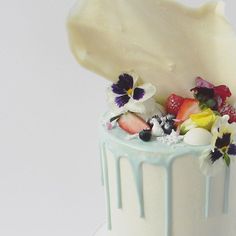 a close up of a cake with fruit and flowers on the top, frosting