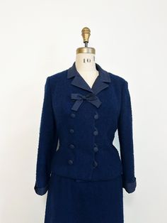 |d e s c r i p t i o n| *circa 1960s *beautiful dark blue nubby wool blend skirt suit  *pencil skirt with nylon zipper and top button  *tailored matching jacket with raw silk blend collar and matching double buttons up front and front bow  *cuffed sleeves  *beautiful blue lining  *true color closest to flat lay photos  |i n f o| tag: unfortunately tag was removed  condition: very good vintage condition, minor general wear. Discoloration at armpits  |m e a s u r e m e n t s| JACKET bust: 38" waist: 36" bottom: 37" length: 21" sleeve length: 19.5" SKIRT waist: 28" hips: 41" (lining goes to 39", may wish to remove) length: 25" est. size: medium  mannequin measurements: bust 35"/waist 25.5"/hips 35" Vintage Blue Skirt Suit For Formal Occasions, Classic Blue Long Sleeve Skirt Suit, Blue Long Sleeve Classic Skirt Suit, Vintage Fitted Skirt Suit With Long Sleeves, Fitted Vintage Skirt Suit With Long Sleeves, Vintage Fitted Long Sleeve Skirt Suit, Fitted Blue Outerwear For Costume, Fitted Navy Retro Outerwear, Navy Fitted Retro Outerwear