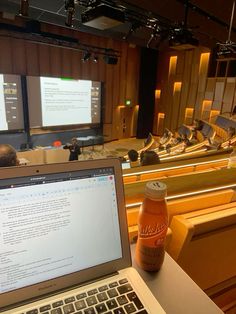 an open laptop computer sitting on top of a table in front of a lecture hall