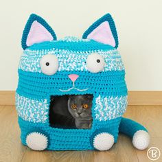 a cat in a crocheted blue and white kitty house