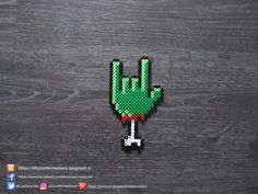 a green pixelated hand making the peace sign with it's fingers on a wooden surface