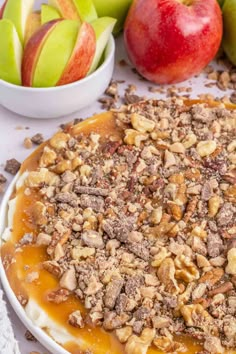 an apple pie with caramel sauce and nuts on top, surrounded by other apples