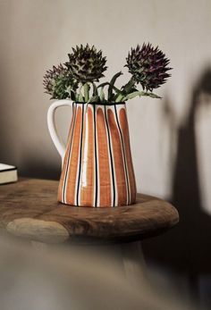 two flowers are in a striped vase on a table