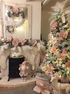 a decorated christmas tree in front of a fireplace with pink and white flowers on it