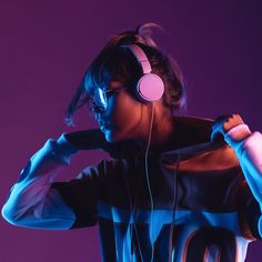 a woman wearing headphones and holding a microphone in front of her face while standing against a purple background