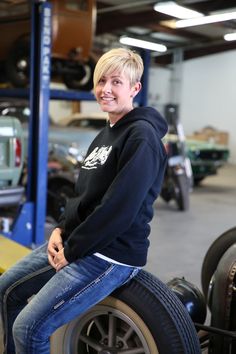 a man sitting on top of a tire in a garage