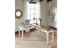 a desk with a laptop on it in front of a window and a plaid rug