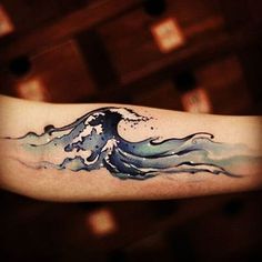 a watercolor wave tattoo on the arm