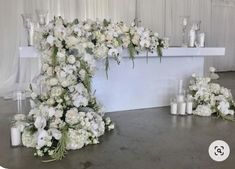 white flowers and candles are arranged on the floor