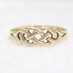 a gold ring with an intertwined design on it's side, sitting on a white surface