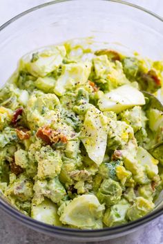 a glass bowl filled with broccoli and potato salad on top of a table