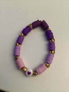 a purple and gold beaded bracelet on a white surface