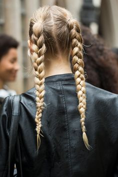 a woman with long blonde hair wearing a black leather jacket and braids in her hair