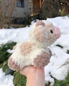 a hand holding a small stuffed animal in the snow