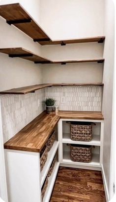 an empty pantry with shelves and baskets on the bottom shelf, next to a wooden floor