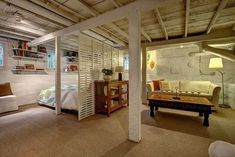 a room with a bed, couch and table in it next to a book shelf