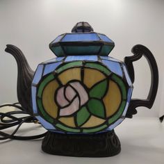 a stained glass teapot sitting on top of a table next to a charger