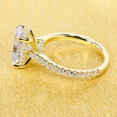 a yellow gold ring with an oval cut diamond surrounded by smaller round diamonds on a golden background