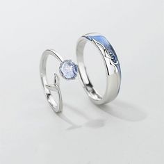 two silver rings with blue and white designs on the sides, one has a diamond