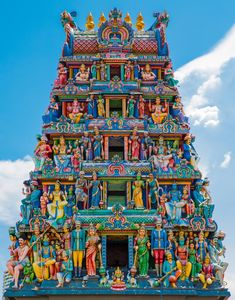 an elaborately decorated tower with statues on it's sides and blue sky in the background