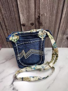 This boho-style upcycled denim handbag was handmade with distressed denim fabric pockets, vintage beige, blue, and green floral cotton fabric, and beige plastic buttons. The removable strap that attaches with Kam snaps. It has unique decorative stitched front and back pockets and a center pocket and shabby chic vintage fabric flowers. Bag - 6 3/4" X 5 1/2" Strap - 43"  Shipped with the USA Thank you for visiting my small biz shop! Vintage Upcycled Shoulder Bag For Everyday Use, Jean Pocket Purse, Upcycled Denim Blue Rectangular Shoulder Bag, Denim Blue Recycled Shoulder Bag With Zipper Pocket, Blue Recycled Denim Shoulder Bag With Zipper Pocket, Denim Handbag, Blue Jean Purses, Jeans Pocket, Jean Purses