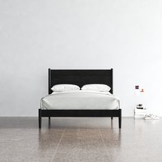 a bed sitting on top of a white floor next to a black headboard and foot board