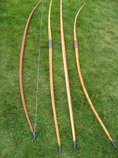 three bows and arrows laying on the grass in front of each other, ready to be used for archery practice