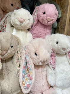 several stuffed animals are lined up in a pile on top of each other and one is pink, the other white