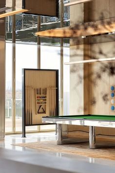 a pool table in the middle of a room with large windows and artwork on the wall