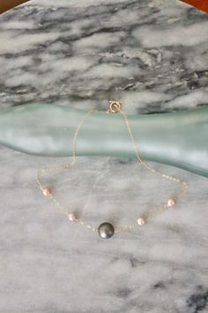 This dainty necklace is made using a 9mm Tahitian Pearl along with 4mm-5mm Edison pearls strung by a 14 karat gold filled chain. The chain is gold filled which means it does not tarnish or turn your skin green. This chain is finished with an elegant and classy 14 karat toggle clasp. Please note: The sale is for ONE necklace. All sales are final. All Violet Kalei Jewelry will arrive packaged in a gift box.  Connect with us on instagram! @violetkaleijewelry Gold Necklace With Tahitian Pearl Round Beads, Classy Necklaces, Pearl Necklace Gold, Surf Jewelry, Classy Necklace, Tahitian Pearl Necklace, Pearl Jewelry Design, Edison Pearls, Necklace Pearl