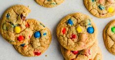 chocolate chip cookies with m & m and m's in the middle on a white surface