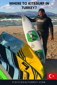 a man holding a surfboard on top of a sandy beach next to the ocean