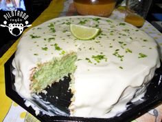 a cake with white frosting and green toppings on a black platter next to a yellow table cloth