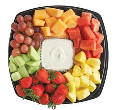 a platter filled with fruit and dip surrounded by grapes, strawberries, melon, pineapples, kiwis