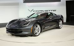 a black sports car is on display at an auto show in front of a corvette logo