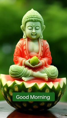 a buddha statue sitting on top of a watermelon bowl with the words good morning