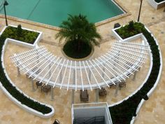 an overhead view of a patio with chairs and tables next to a swimming pool, surrounded by palm trees