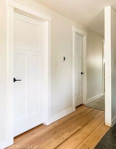 an empty room with white walls and wood floors is seen in this image from the front door