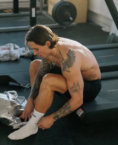 a shirtless man sitting on top of a gym floor