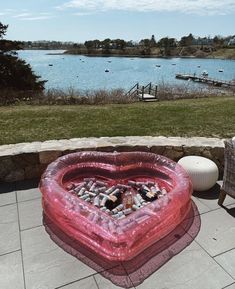 an inflatable heart shaped object on the ground next to a body of water