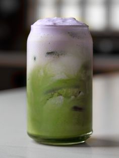 a green drink is sitting on a table with ice and water in the bottom half